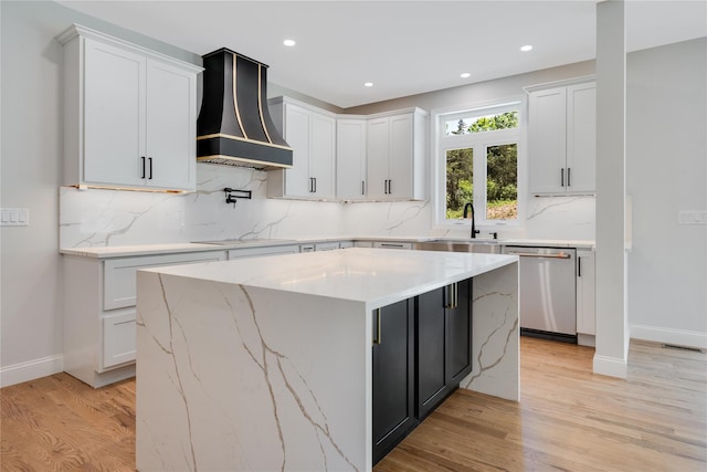 kitchen featuring premium range hood, dishwasher, a sink, and light wood finished floors