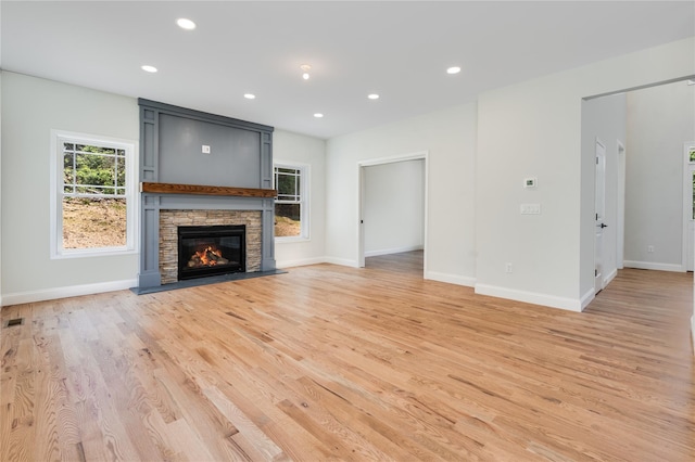 unfurnished living room featuring recessed lighting, baseboards, light wood-style floors, and a fireplace