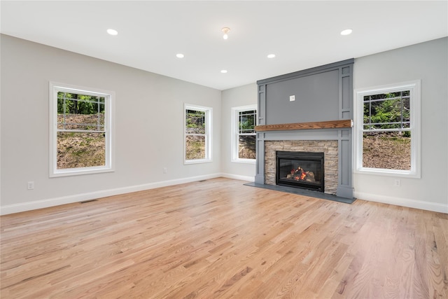 unfurnished living room with light wood finished floors, visible vents, baseboards, recessed lighting, and a fireplace