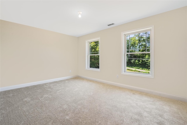 empty room featuring visible vents, baseboards, and carpet