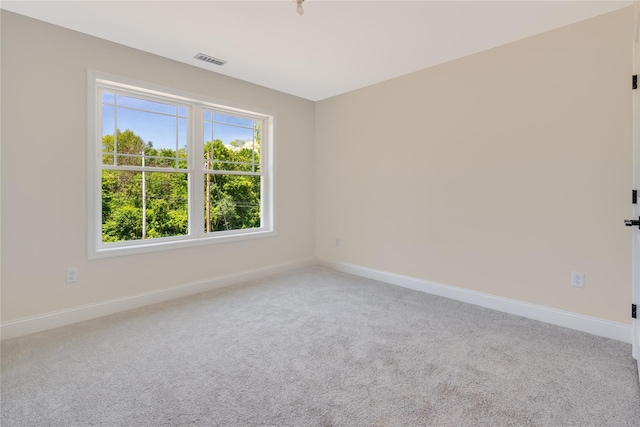 carpeted spare room with visible vents and baseboards