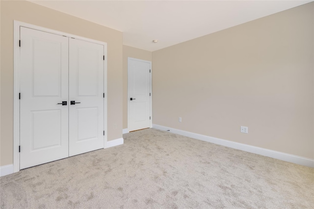 unfurnished bedroom featuring baseboards, carpet floors, and a closet