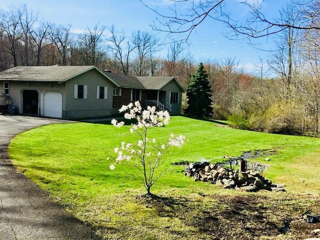 view of front of home featuring aphalt driveway, a garage, and a front lawn