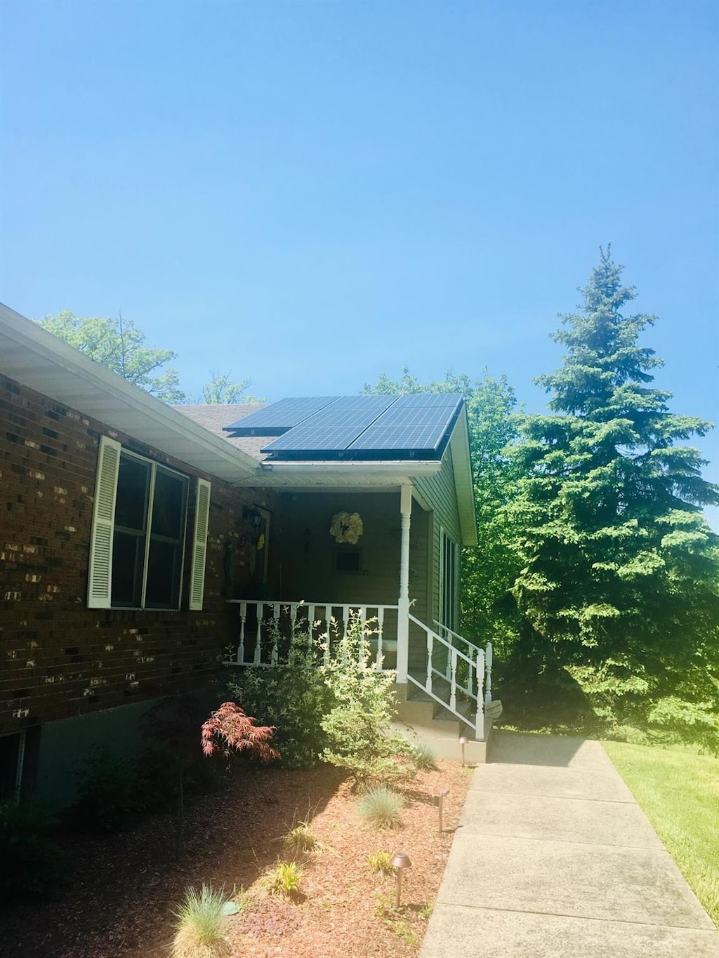 view of side of home with covered porch and roof mounted solar panels