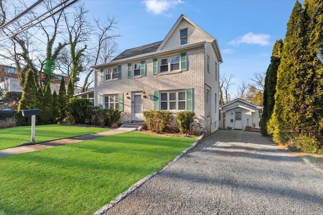 view of front facade with gravel driveway, a front yard, and brick siding