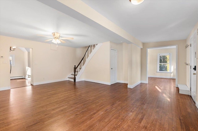 unfurnished living room featuring stairway, wood finished floors, baseboards, ceiling fan, and a baseboard heating unit