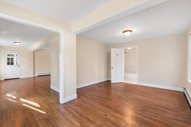 empty room with baseboard heating, a baseboard heating unit, baseboards, and wood finished floors