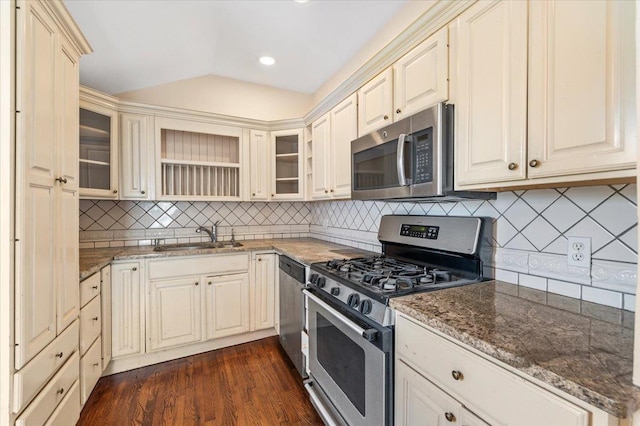 kitchen featuring stone counters, lofted ceiling, a sink, stainless steel appliances, and dark wood-type flooring