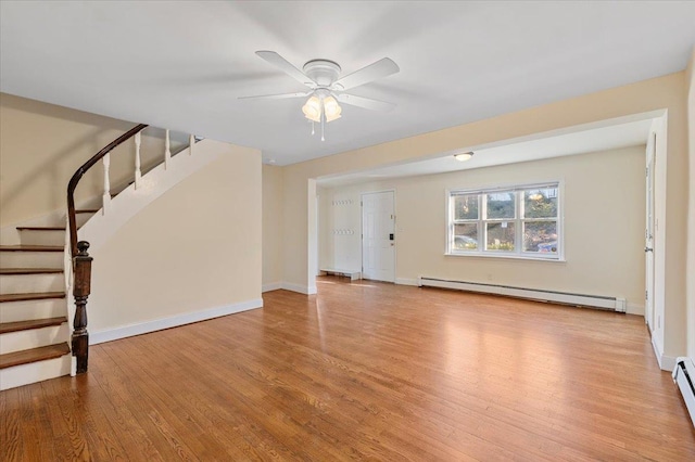 unfurnished living room with stairway, baseboards, baseboard heating, and wood finished floors