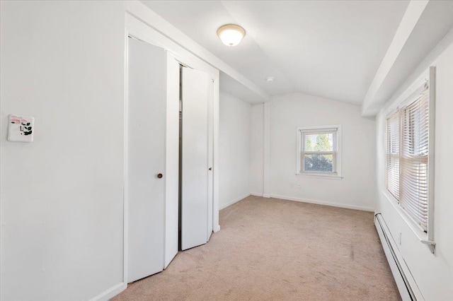 unfurnished bedroom featuring baseboards, lofted ceiling, a closet, light carpet, and baseboard heating