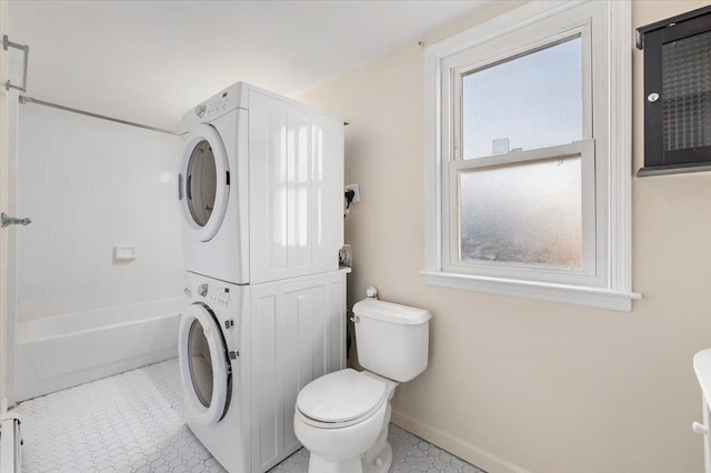 bathroom featuring tile patterned floors, baseboards, toilet, and stacked washing maching and dryer