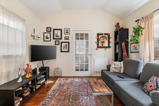 living room with a wealth of natural light, dark wood finished floors, and vaulted ceiling