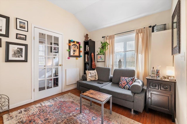 living room featuring vaulted ceiling, wood finished floors, and baseboards