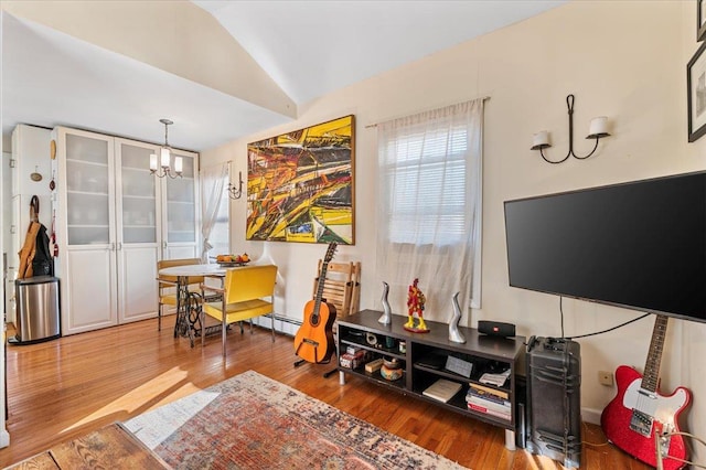 interior space featuring a chandelier, lofted ceiling, and wood finished floors