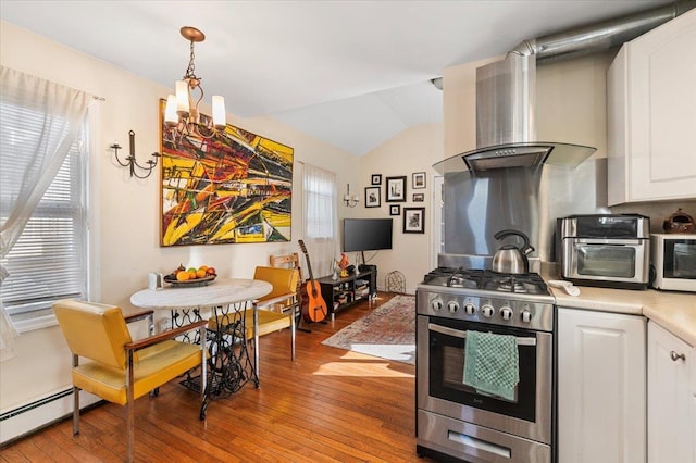 kitchen with light countertops, wall chimney range hood, light wood-style flooring, and stainless steel gas stove