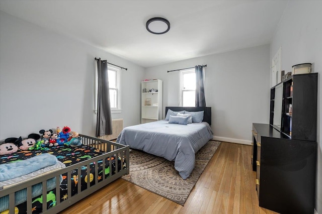 bedroom featuring radiator heating unit, baseboards, and wood-type flooring