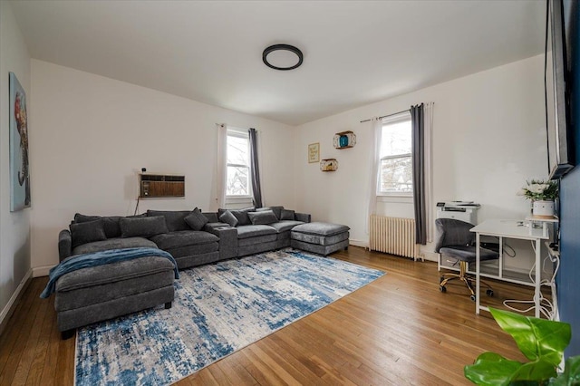 living area with a healthy amount of sunlight, radiator, baseboards, and wood finished floors