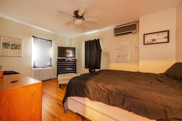 bedroom with a wall mounted air conditioner, a ceiling fan, radiator heating unit, and light wood finished floors