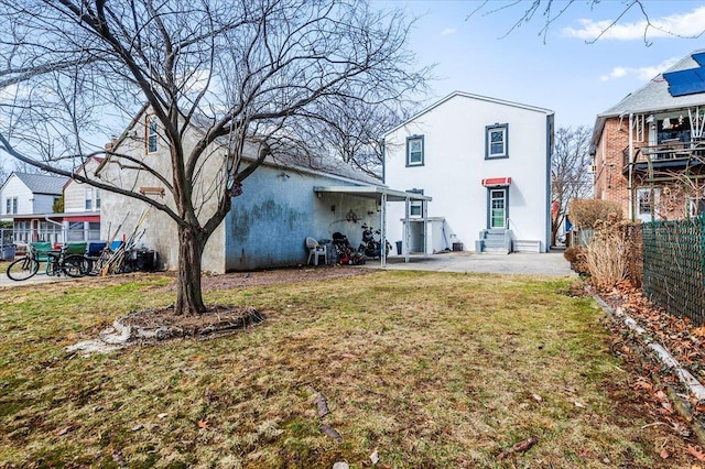 back of property with stucco siding, fence, a lawn, and entry steps