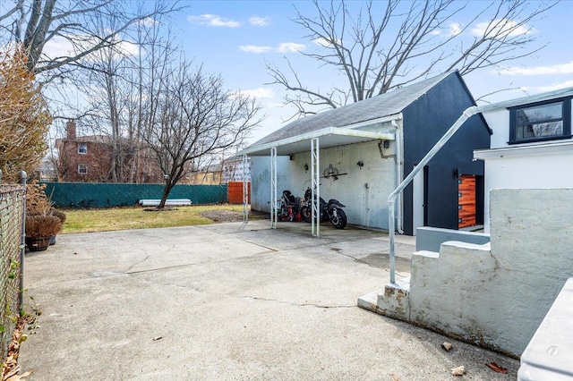 view of patio / terrace featuring an attached carport, driveway, and fence