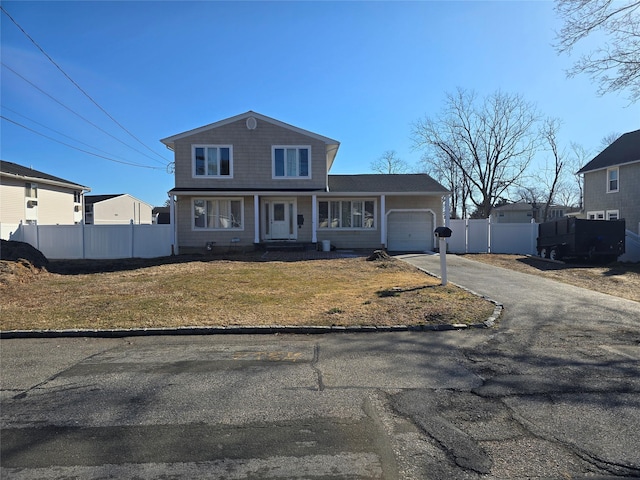 view of front of home featuring aphalt driveway, an attached garage, a front yard, and fence