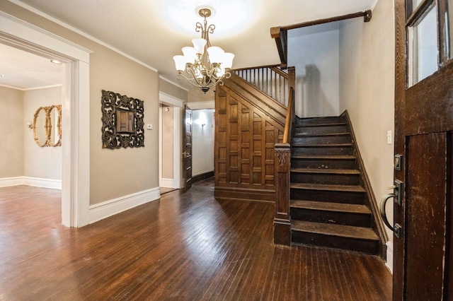 staircase featuring baseboards, a notable chandelier, wood finished floors, and ornamental molding