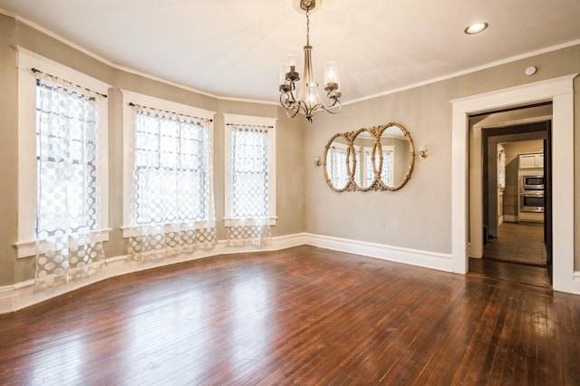 empty room with a notable chandelier, a healthy amount of sunlight, wood-type flooring, and ornamental molding