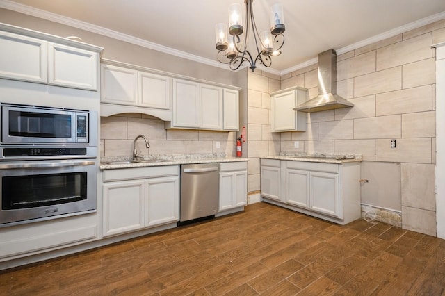 kitchen with a sink, appliances with stainless steel finishes, crown molding, wall chimney range hood, and decorative backsplash