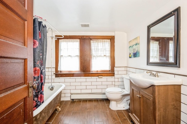 bathroom with visible vents, a wainscoted wall, wood finished floors, tile walls, and a baseboard radiator