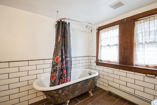 full bath featuring visible vents, baseboard heating, wainscoting, wood finished floors, and tile walls