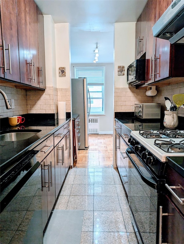 kitchen with range hood, radiator, freestanding refrigerator, black microwave, and gas range