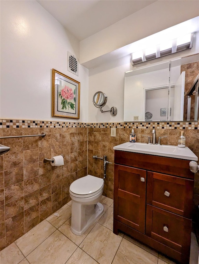 bathroom featuring vanity, tile walls, toilet, and visible vents