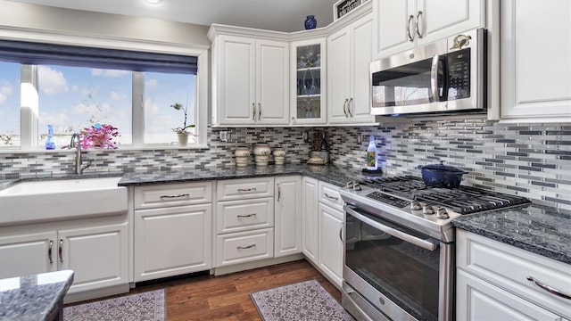 kitchen with dark wood-style flooring, a sink, white cabinets, glass insert cabinets, and appliances with stainless steel finishes