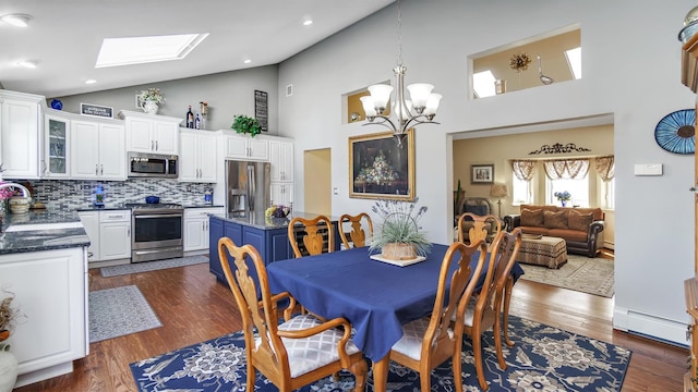 dining room featuring dark wood-style floors, a chandelier, baseboard heating, and a skylight