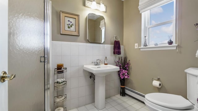 bathroom with a baseboard radiator, tile patterned flooring, a shower stall, tile walls, and toilet