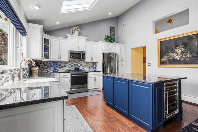 2100 Duck Pond Rd, Cutchogue, NY 11935 - kitchen with appliances with stainless steel finishes, blue cabinets, beverage cooler, backsplash, and white cabinetry