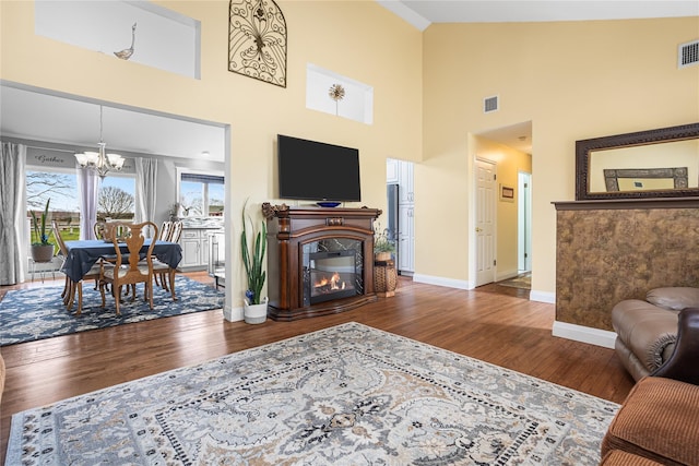 2100 Duck Pond Rd, Cutchogue, NY 11935 - living area featuring a chandelier, wood finished floors, baseboards, a towering ceiling, and a glass covered fireplace