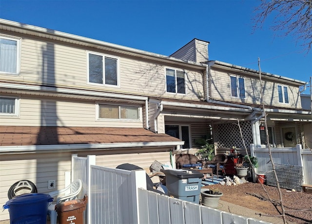 back of property with a chimney and fence