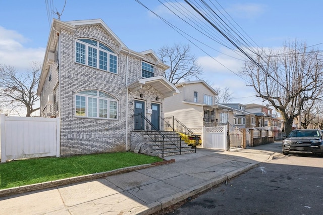 view of front of house featuring a residential view, brick siding, and fence