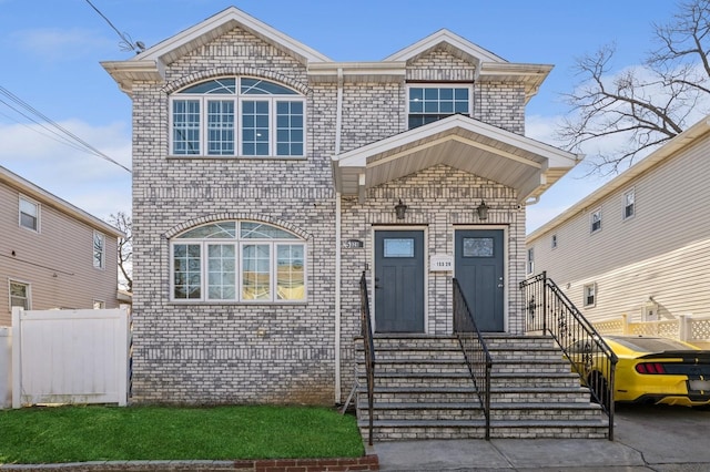 view of front facade with brick siding and fence