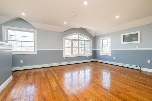 unfurnished room featuring baseboards, wood-type flooring, baseboard heating, and vaulted ceiling