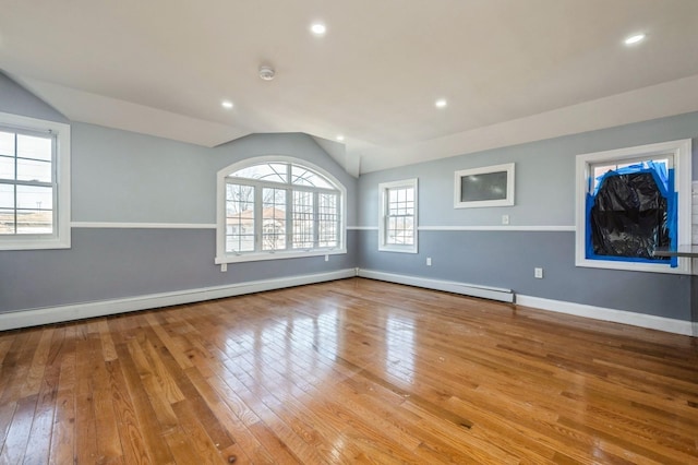 spare room featuring baseboards, lofted ceiling, recessed lighting, hardwood / wood-style flooring, and baseboard heating