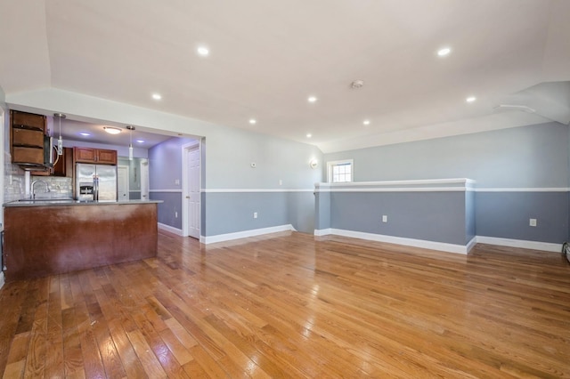 unfurnished living room with recessed lighting, baseboards, and light wood finished floors