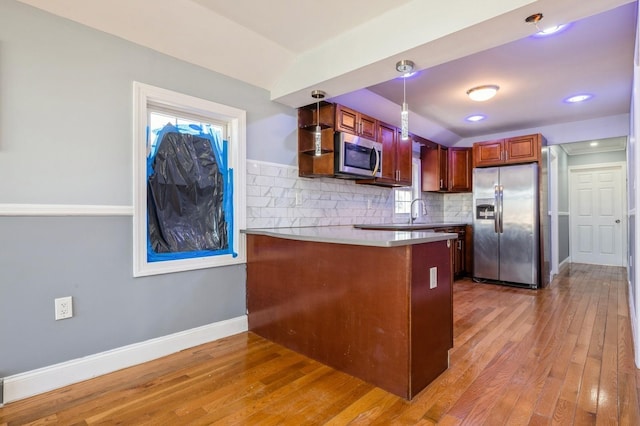 kitchen with baseboards, a peninsula, stainless steel appliances, light wood-style floors, and backsplash