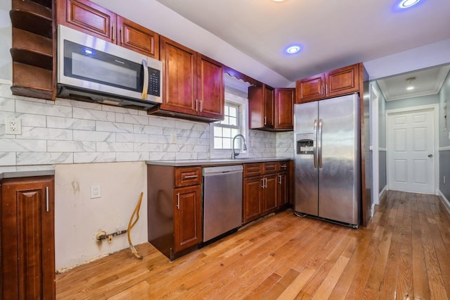 kitchen with light wood finished floors, recessed lighting, a sink, decorative backsplash, and appliances with stainless steel finishes