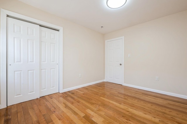 unfurnished bedroom with light wood-style floors, baseboards, and a closet