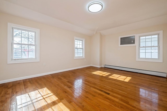 unfurnished room featuring baseboards, hardwood / wood-style floors, lofted ceiling, and a baseboard radiator