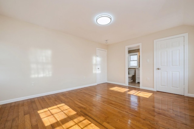 empty room featuring baseboards and wood-type flooring