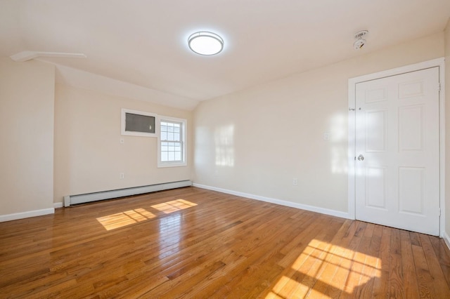 spare room with a baseboard heating unit, baseboards, and light wood-style flooring