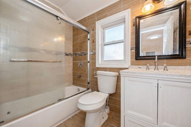 bathroom featuring vanity, wood finished floors, enclosed tub / shower combo, tile walls, and toilet